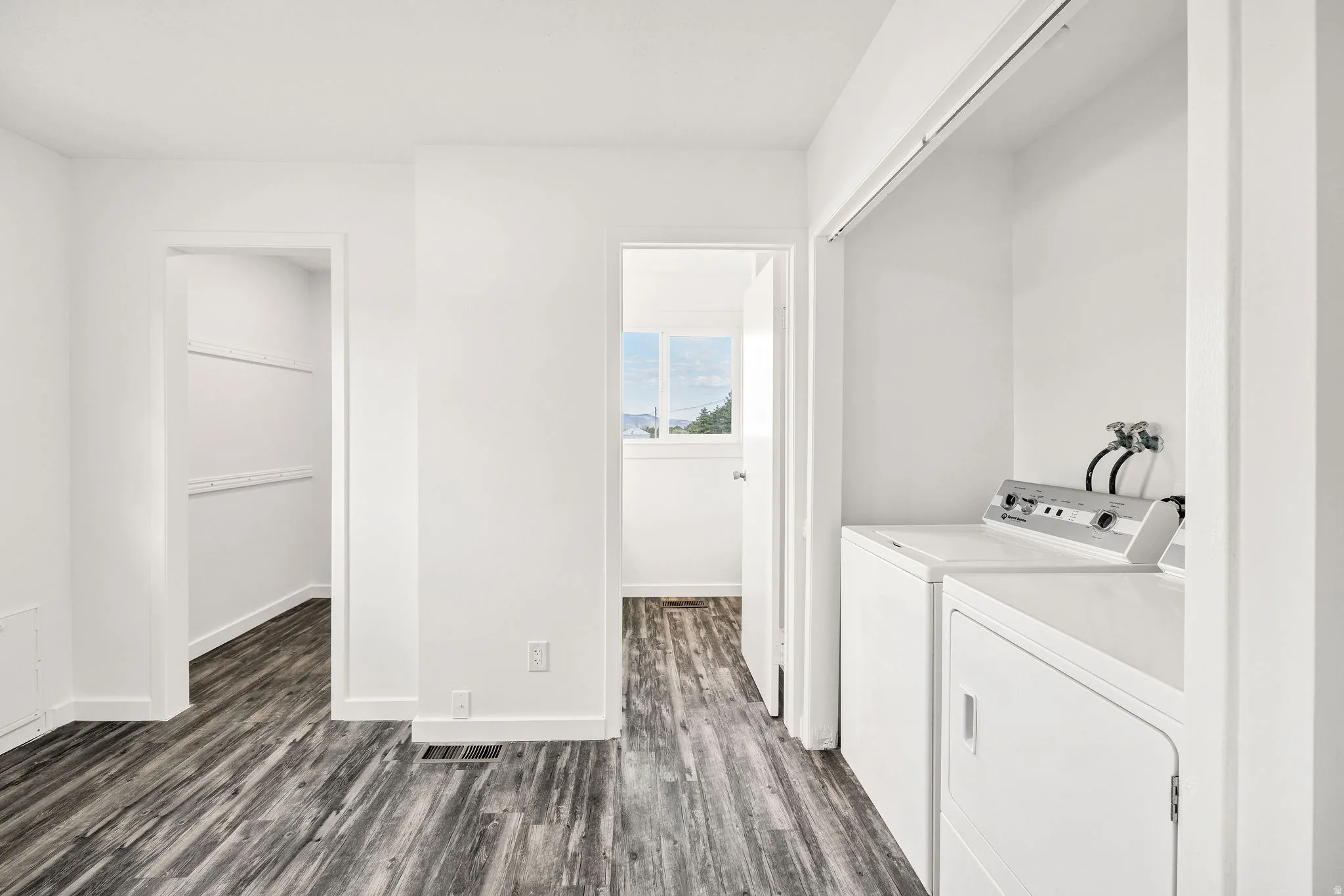Laundry area featuring dark wood-style flooring and independent washer and dryer
