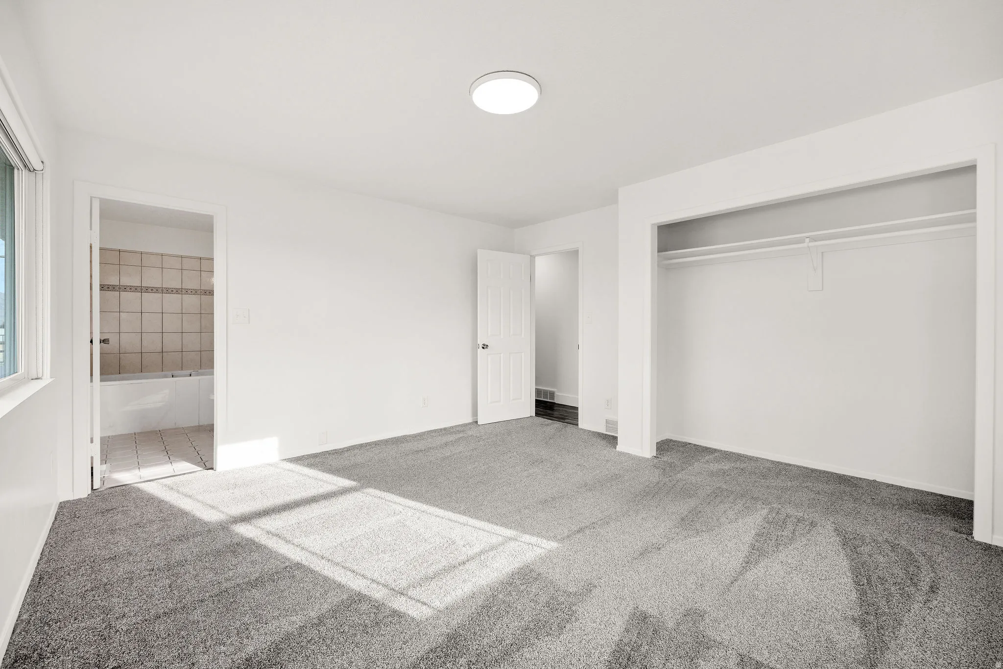 Unfurnished bedroom featuring carpet flooring, ensuite bath, and a closet