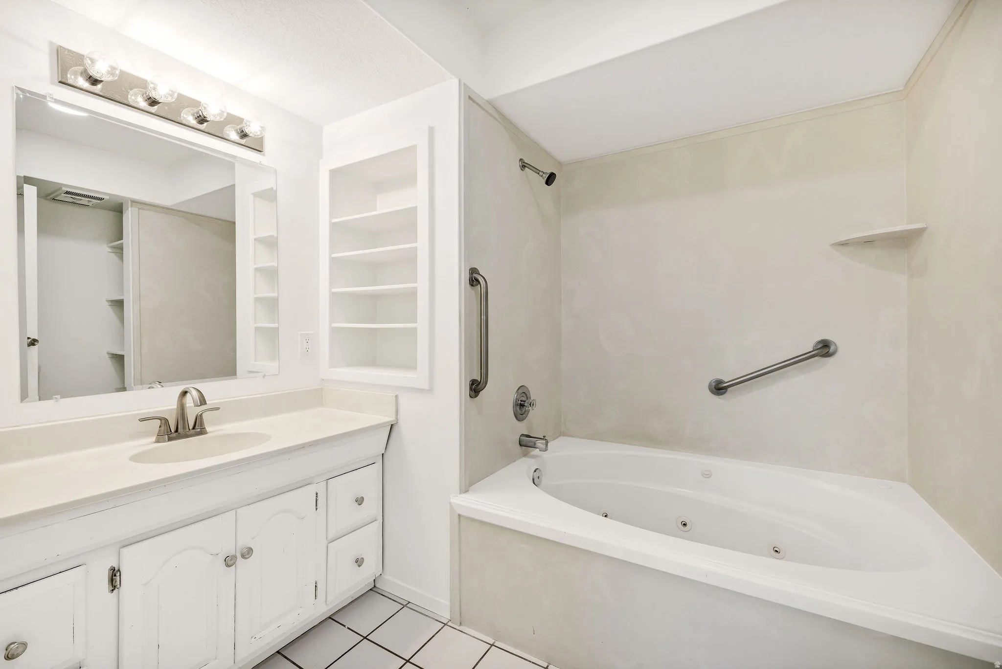 Bathroom featuring vanity, built in shelves, light tile patterned floors, and a combined bath / shower with jetted tub