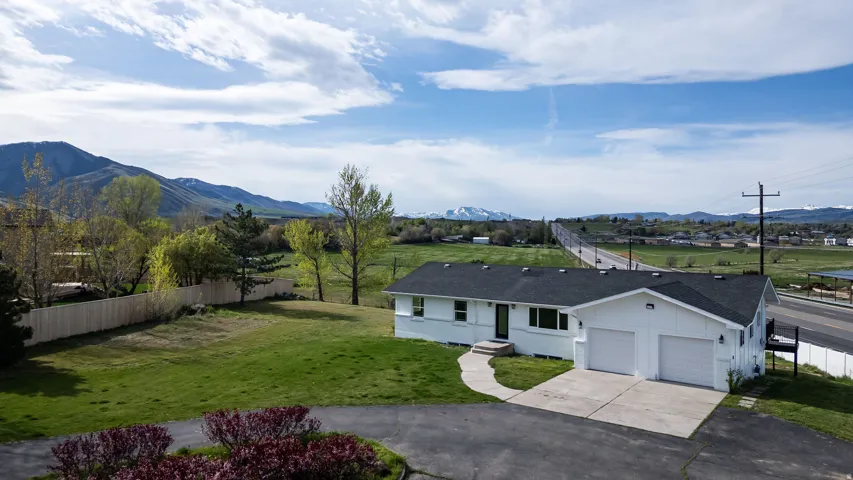 View of front of house with driveway, a garage, roof with shingles, and a mountain view