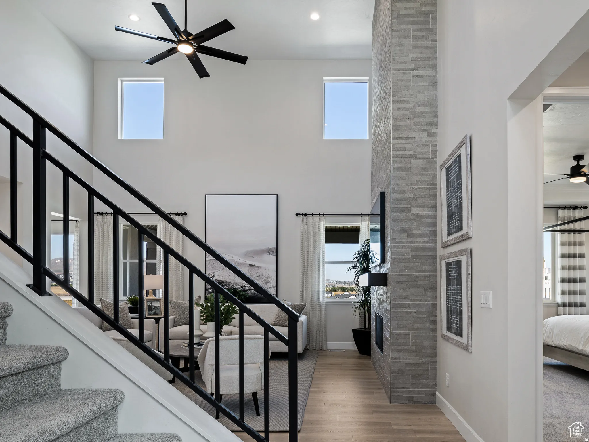 Staircase featuring ceiling fan, wood finished floors, a high ceiling, and recessed lighting