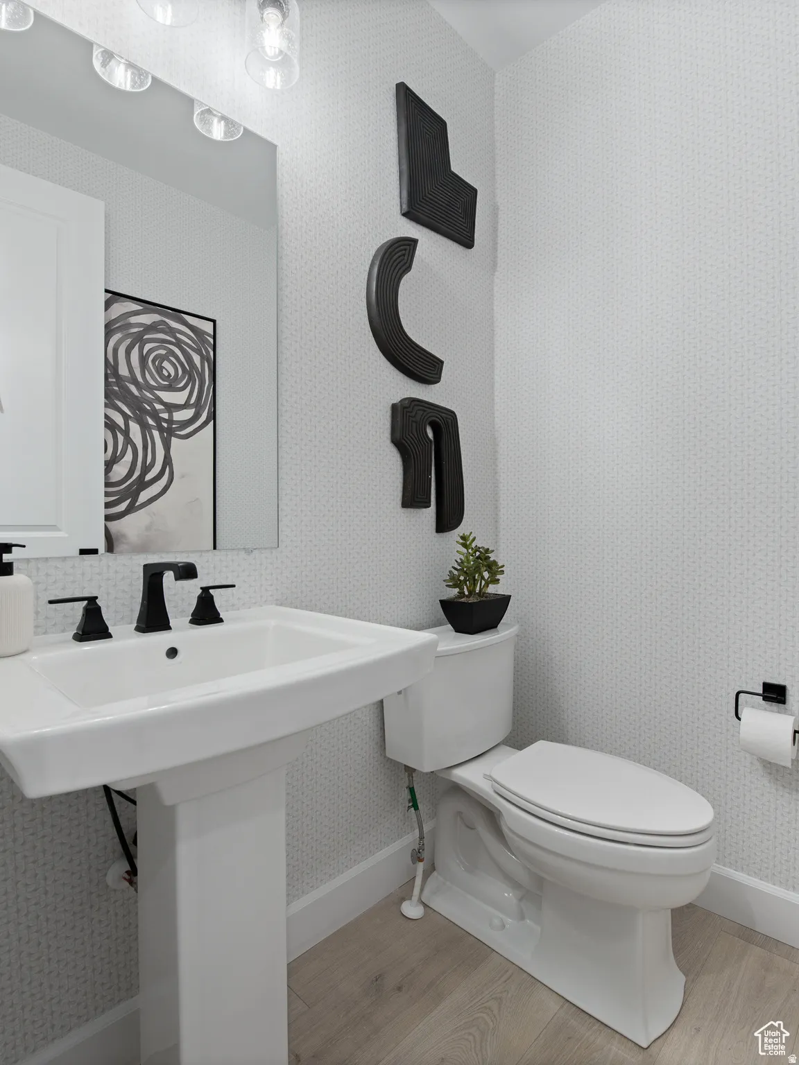 Bathroom featuring wallpapered walls and light wood-type flooring