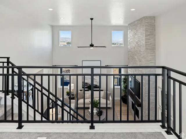 Corridor with an upstairs landing, plenty of natural light, a high ceiling, and recessed lighting