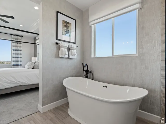 Full bath featuring a freestanding tub, ensuite bathroom, and light wood-style floors