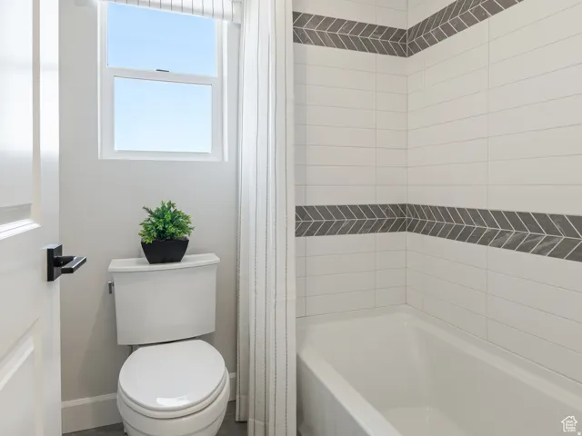 Full bath with toilet and shower / bath combination with curtain