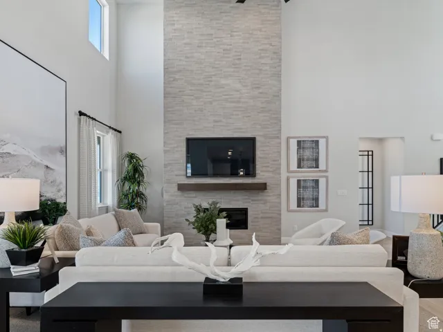 Living room with a high ceiling, a fireplace, and plenty of natural light