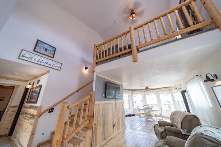 Living room featuring a ceiling fan, wood walls, wainscoting, and hardwood / wood-style flooring