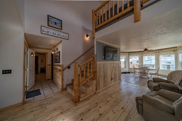 Living room with light wood-style floors, wainscoting, ceiling fan, and wood walls