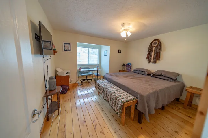 Bedroom featuring light wood-type flooring, a textured ceiling, and a ceiling fan