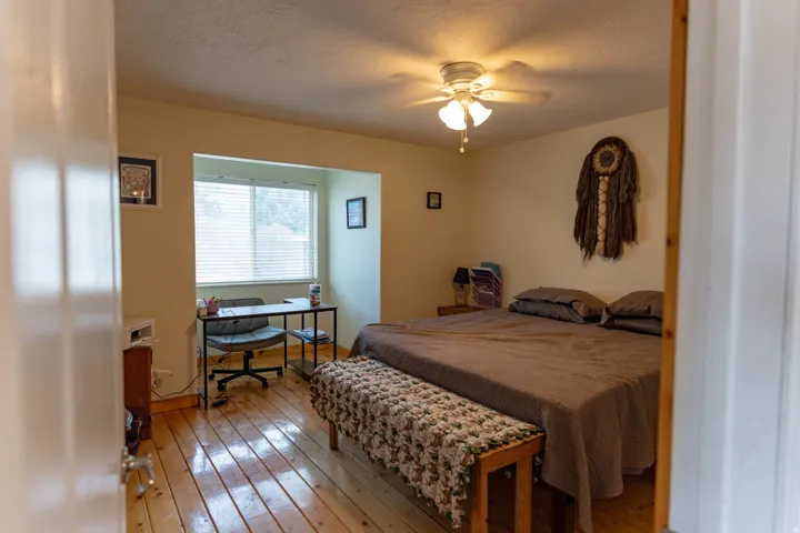 Bedroom featuring hardwood / wood-style floors, a textured ceiling, a ceiling fan, and an office area