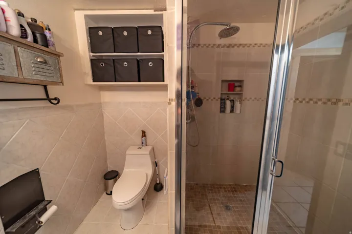 Full bathroom featuring a stall shower, tile walls, light tile patterned floors, and wainscoting