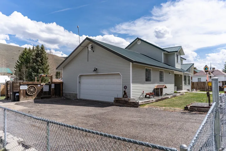 View of side of home featuring a metal roof, asphalt driveway, and an attached garage