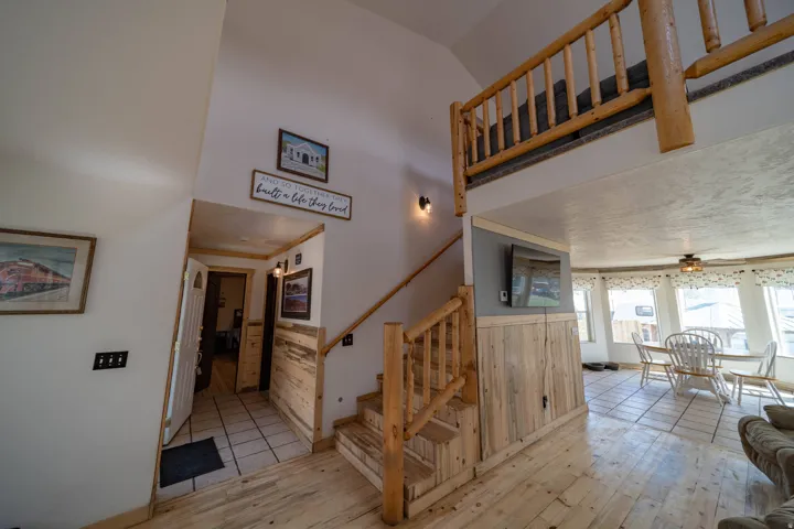 Stairs with hardwood / wood-style flooring, a wainscoted wall, ceiling fan, wooden walls, and a high ceiling