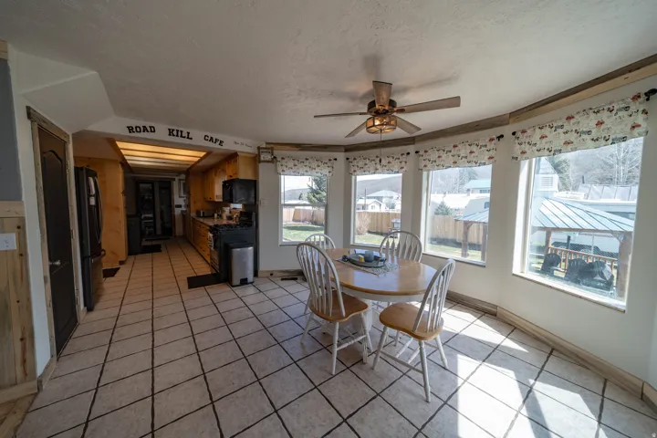 Dining space featuring ceiling fan, light tile patterned flooring, healthy amount of natural light, and a textured ceiling