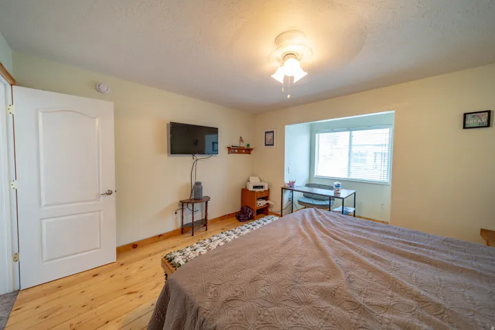 Bedroom with light wood-type flooring, a textured ceiling, and ceiling fan