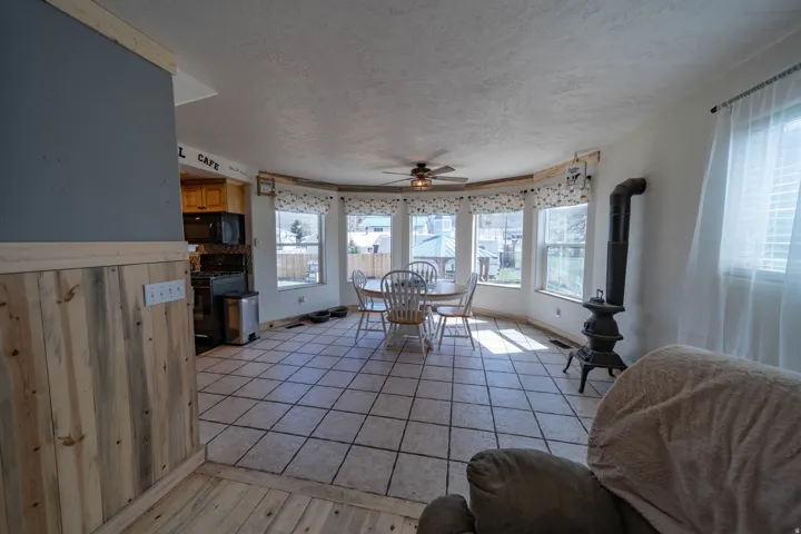 Dining room with a ceiling fan, a textured ceiling, light wood-type flooring, and plenty of natural light