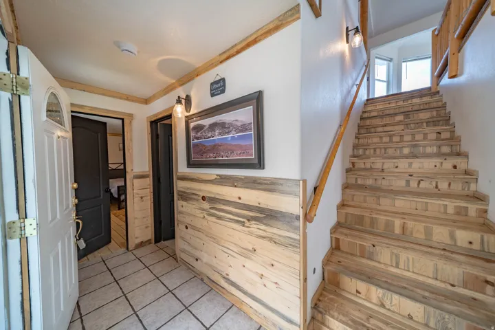 Stairs with tile patterned floors and a wainscoted wall