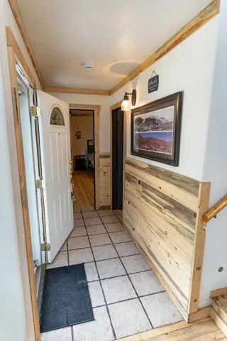 Hallway featuring light tile patterned floors, wainscoting, and wooden walls
