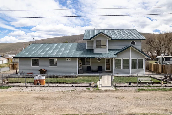View of front of property featuring a metal roof, a fenced front yard, a gate, and a patio area