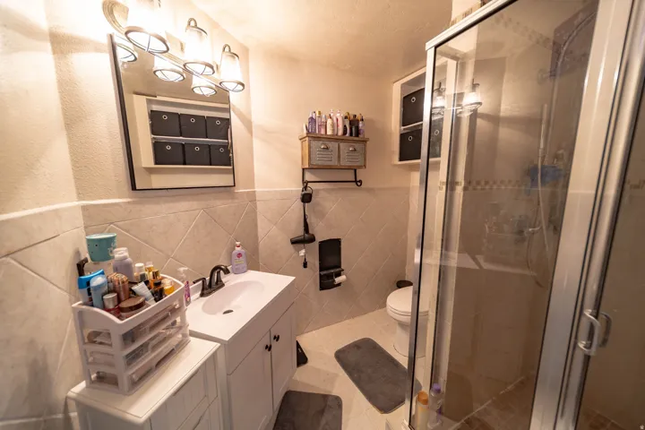 Bathroom with vanity, tile walls, a shower stall, wainscoting, and light tile patterned floors