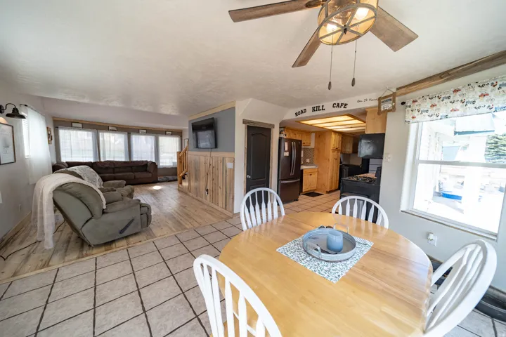 Dining room featuring light tile patterned flooring, ceiling fan, and a wainscoted wall