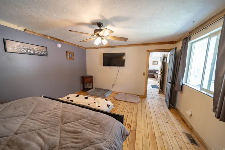 Bedroom with light wood-type flooring, a textured ceiling, and a ceiling fan