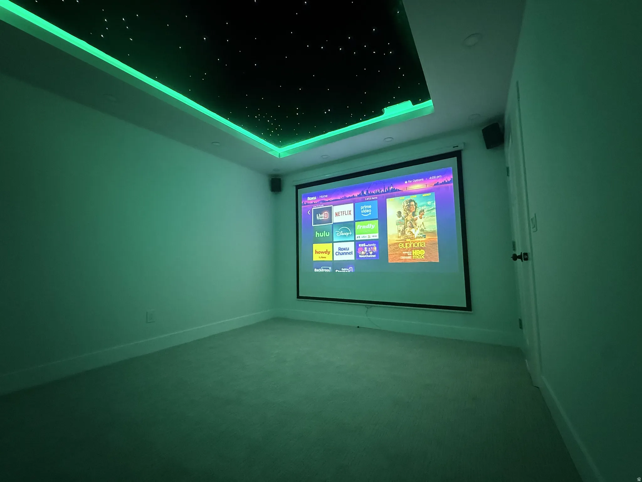 Carpeted cinema room with a raised ceiling and baseboards