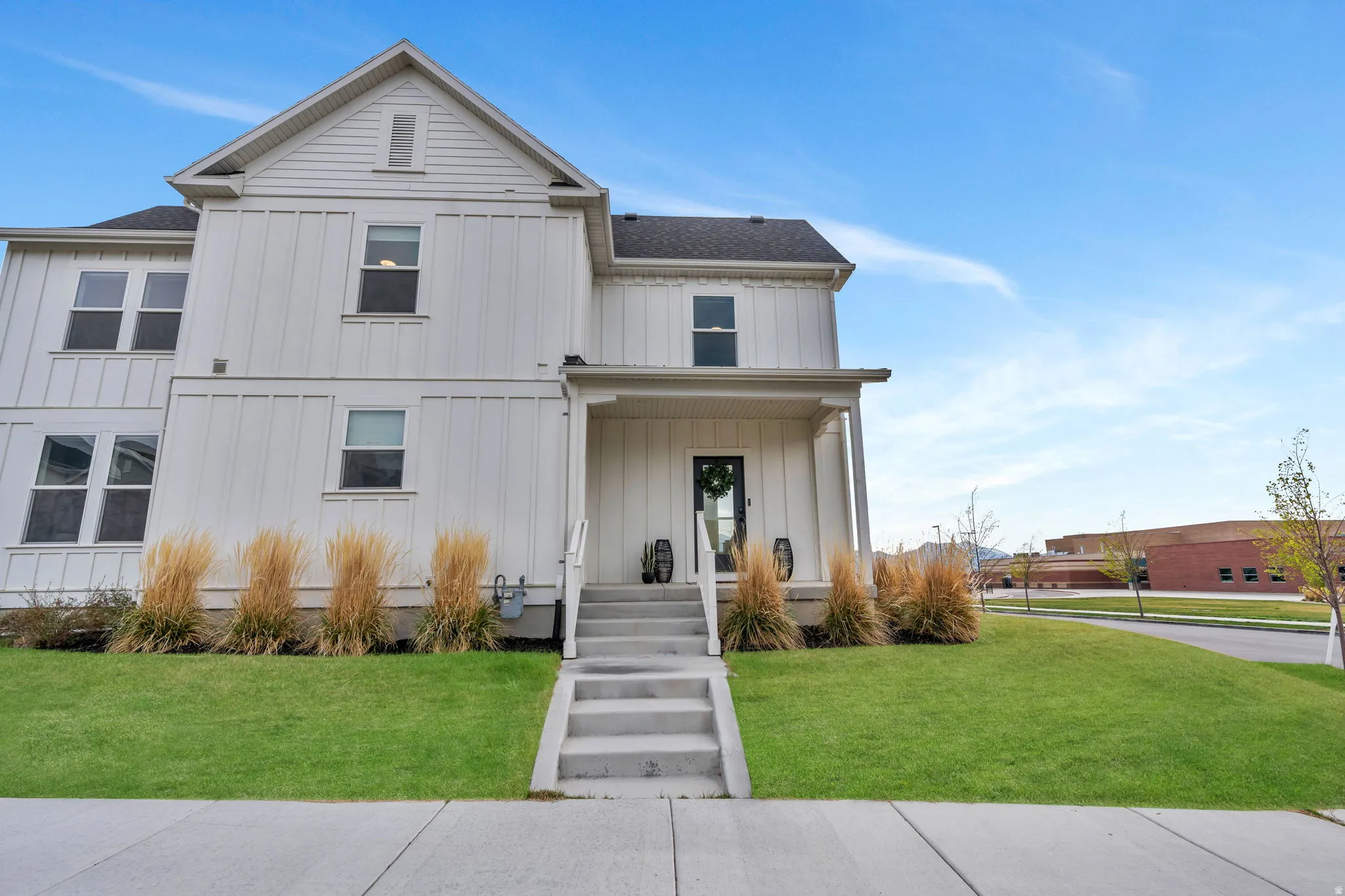 Modern farmhouse with board and batten siding, a front yard, and covered porch
