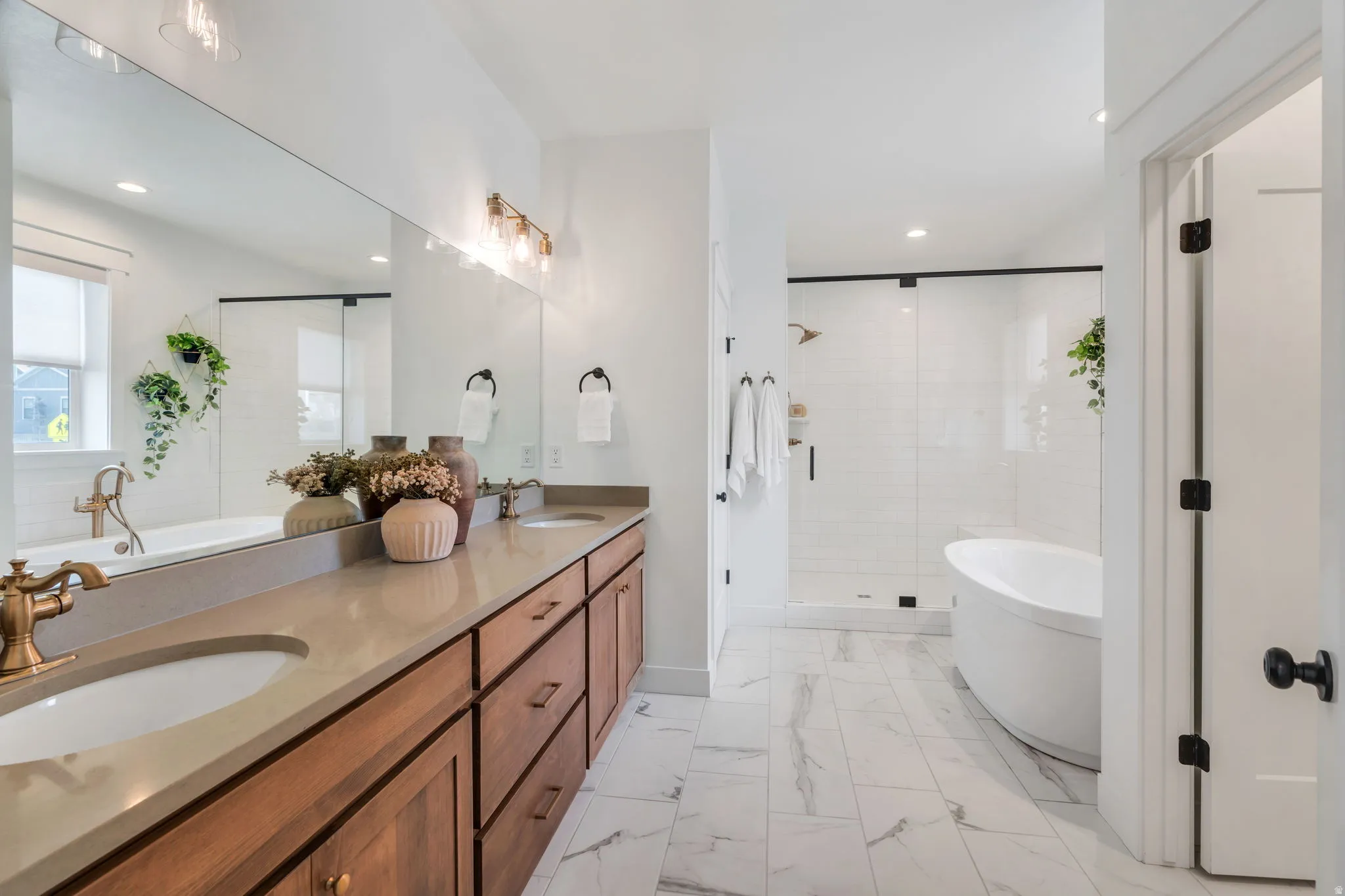Bathroom with a freestanding bath, double vanity, a stall shower, light marble finish floors, and recessed lighting