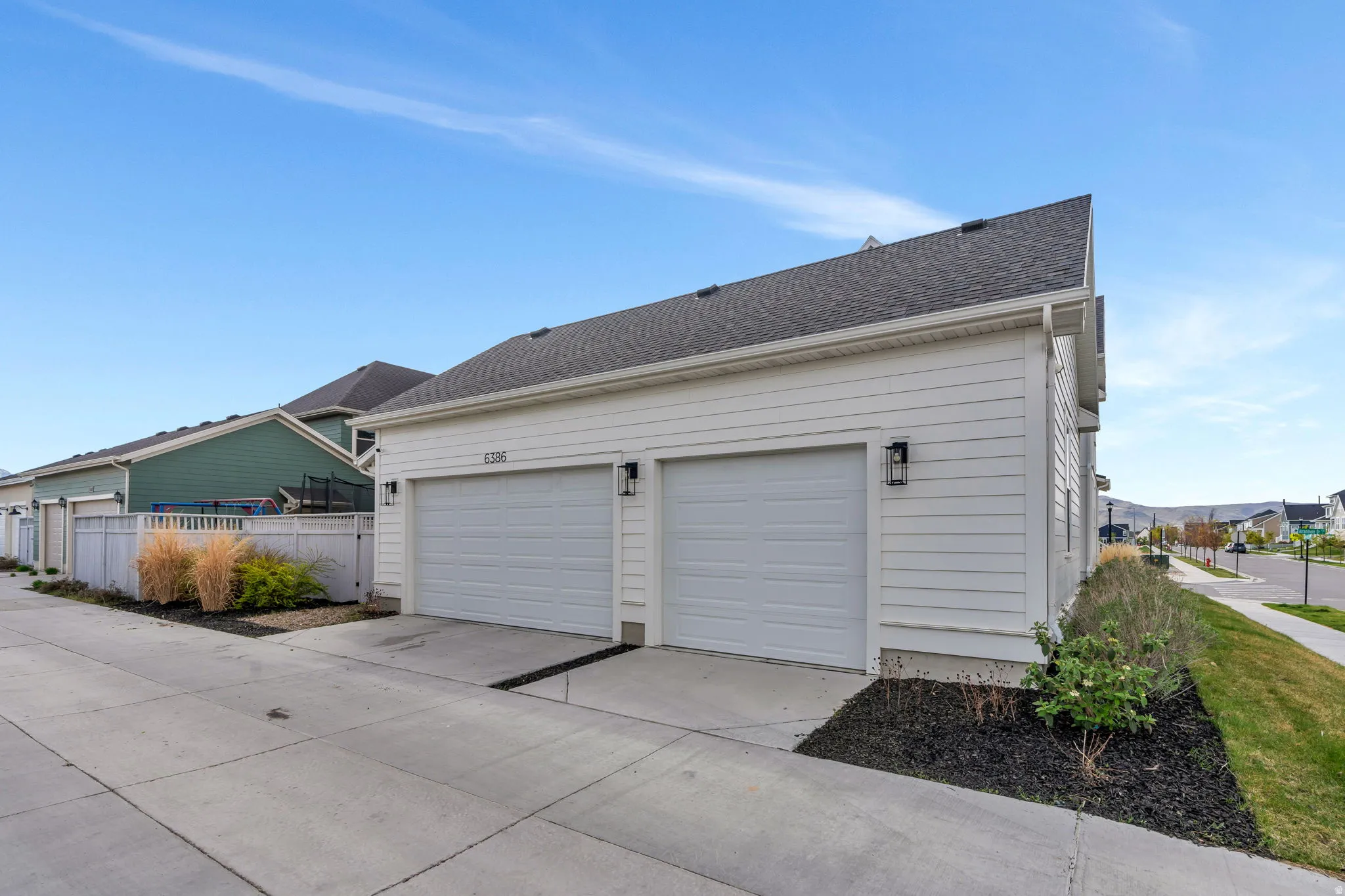 View of side of property featuring driveway, roof with shingles, and a garage