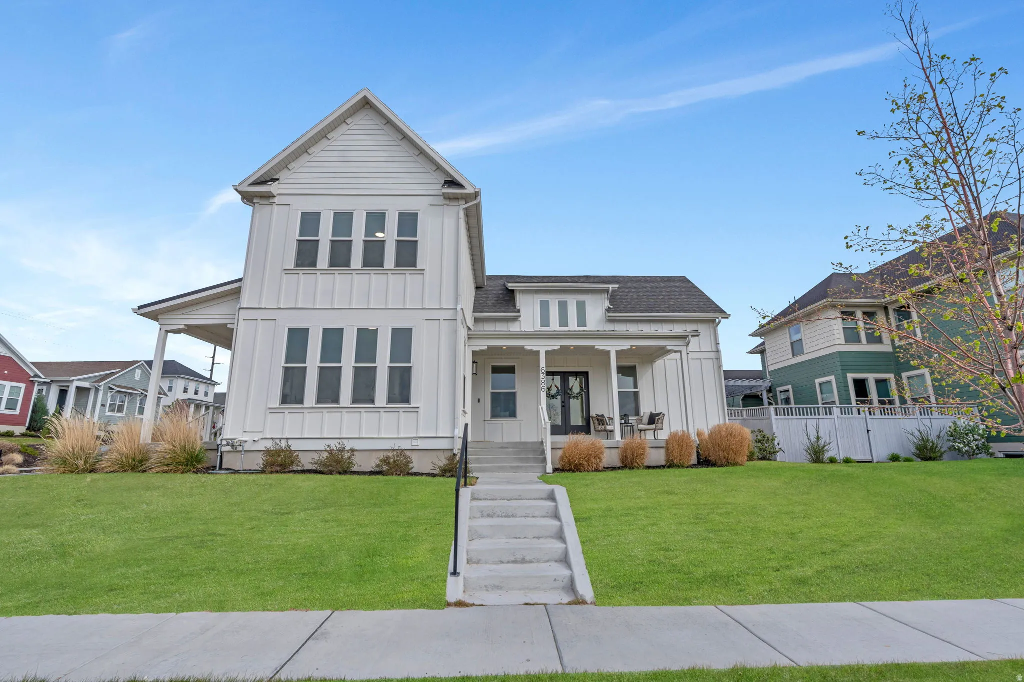 Modern farmhouse style home with board and batten siding, a porch, and a front yard
