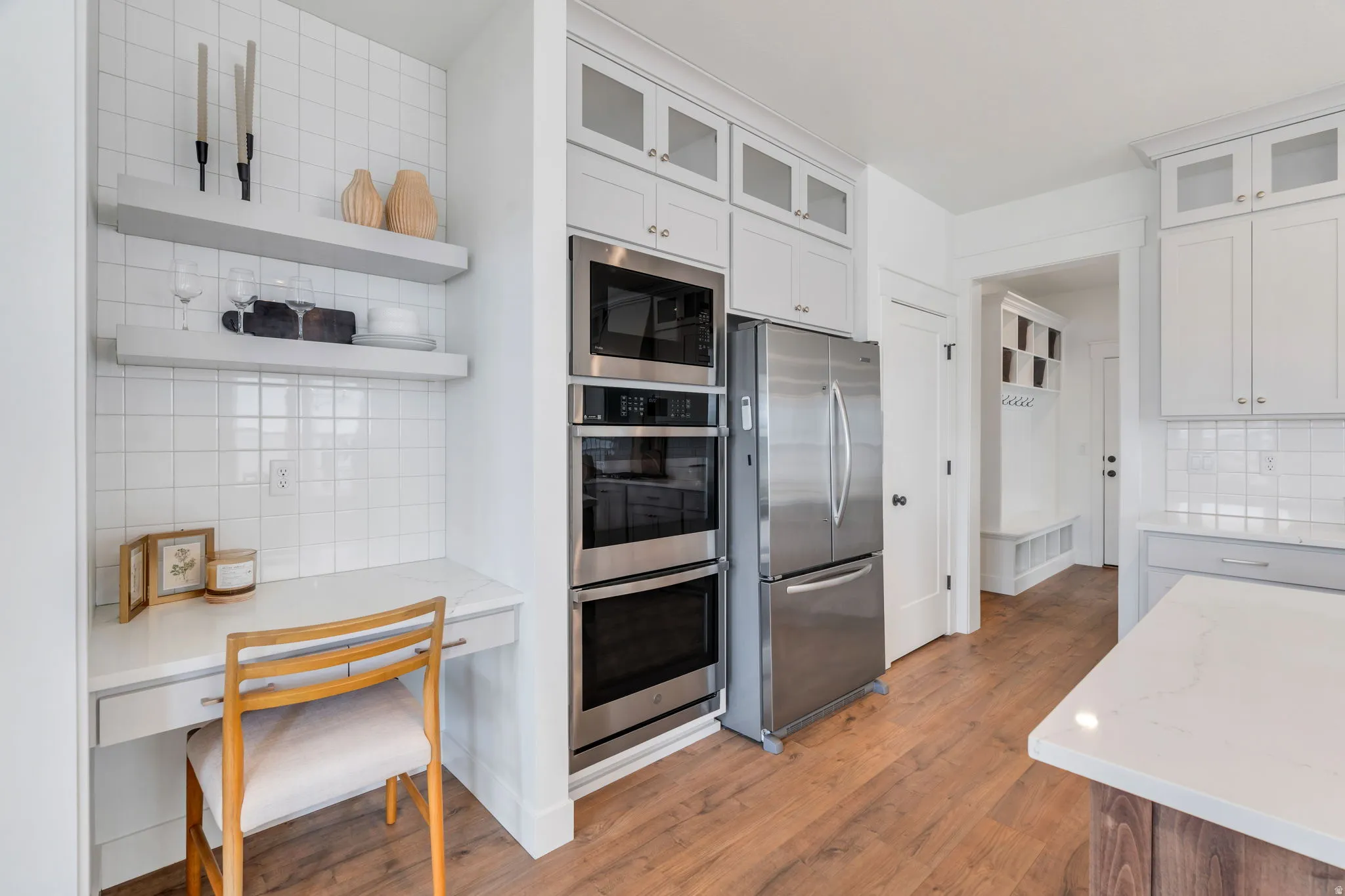 Kitchen featuring backsplash, light stone counters, glass fronted cabinets, and stainless steel appliances