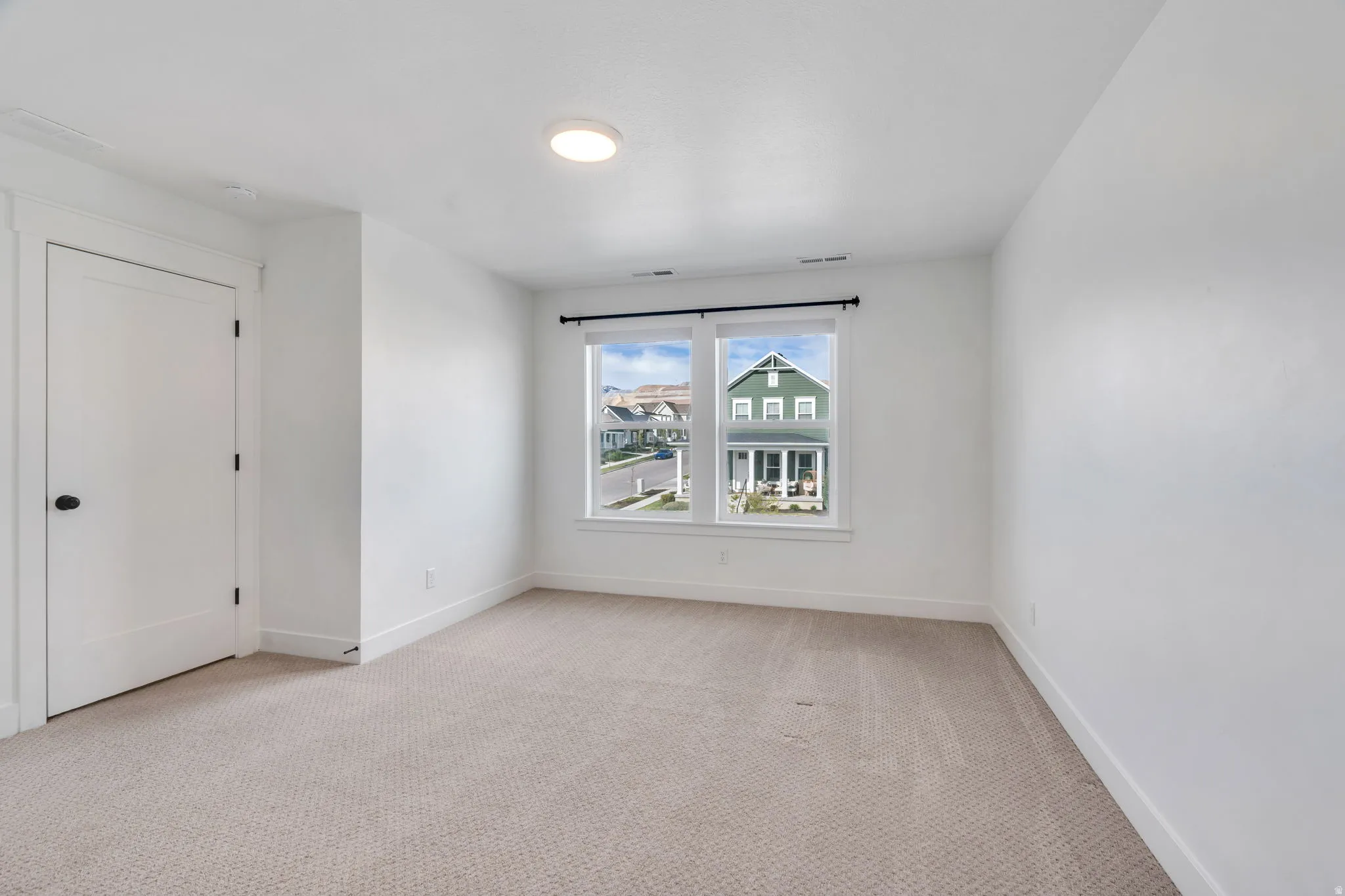 Spare room featuring light carpet and baseboards