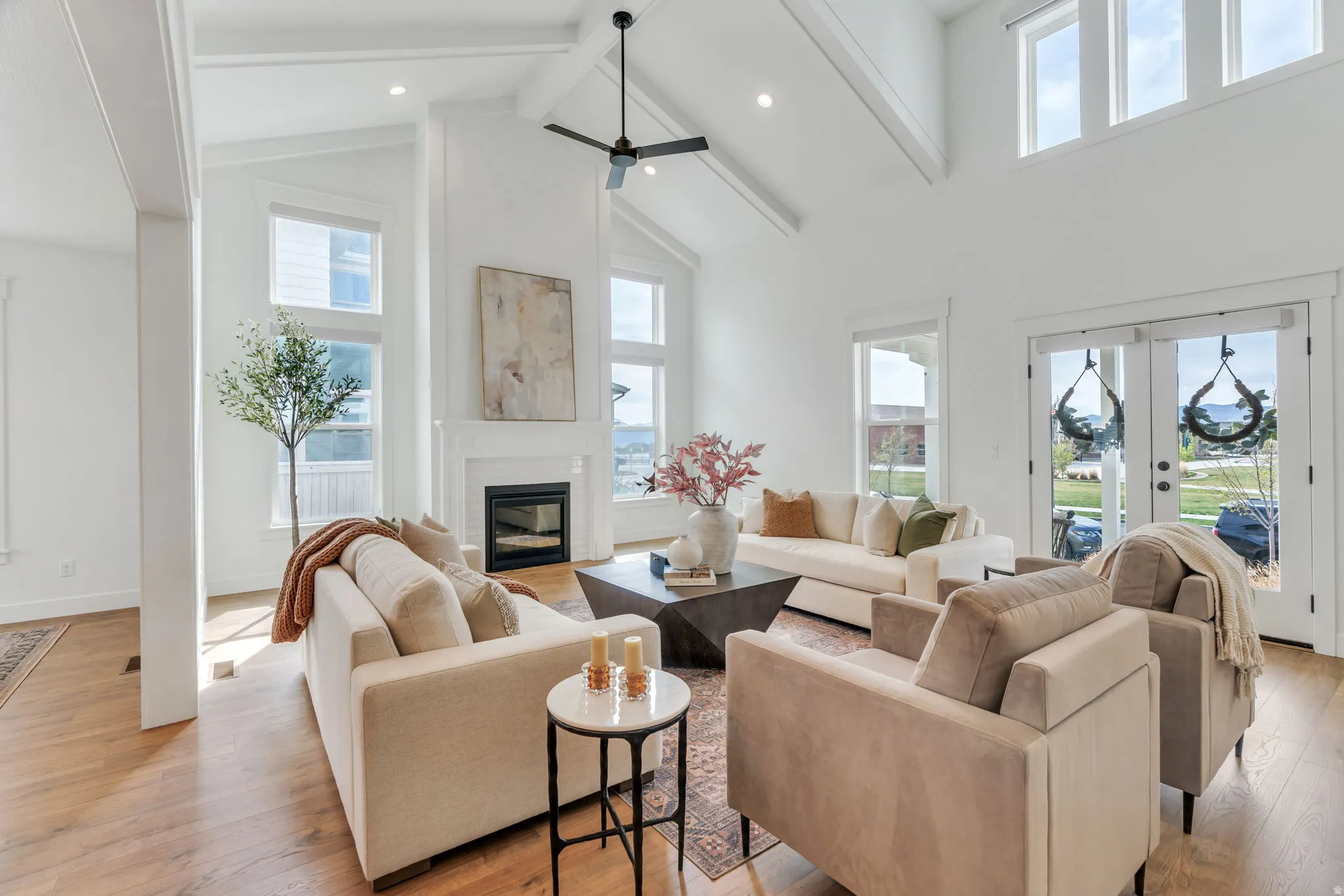 Living area with light wood-type flooring, plenty of natural light, french doors, a glass covered fireplace, and recessed lighting