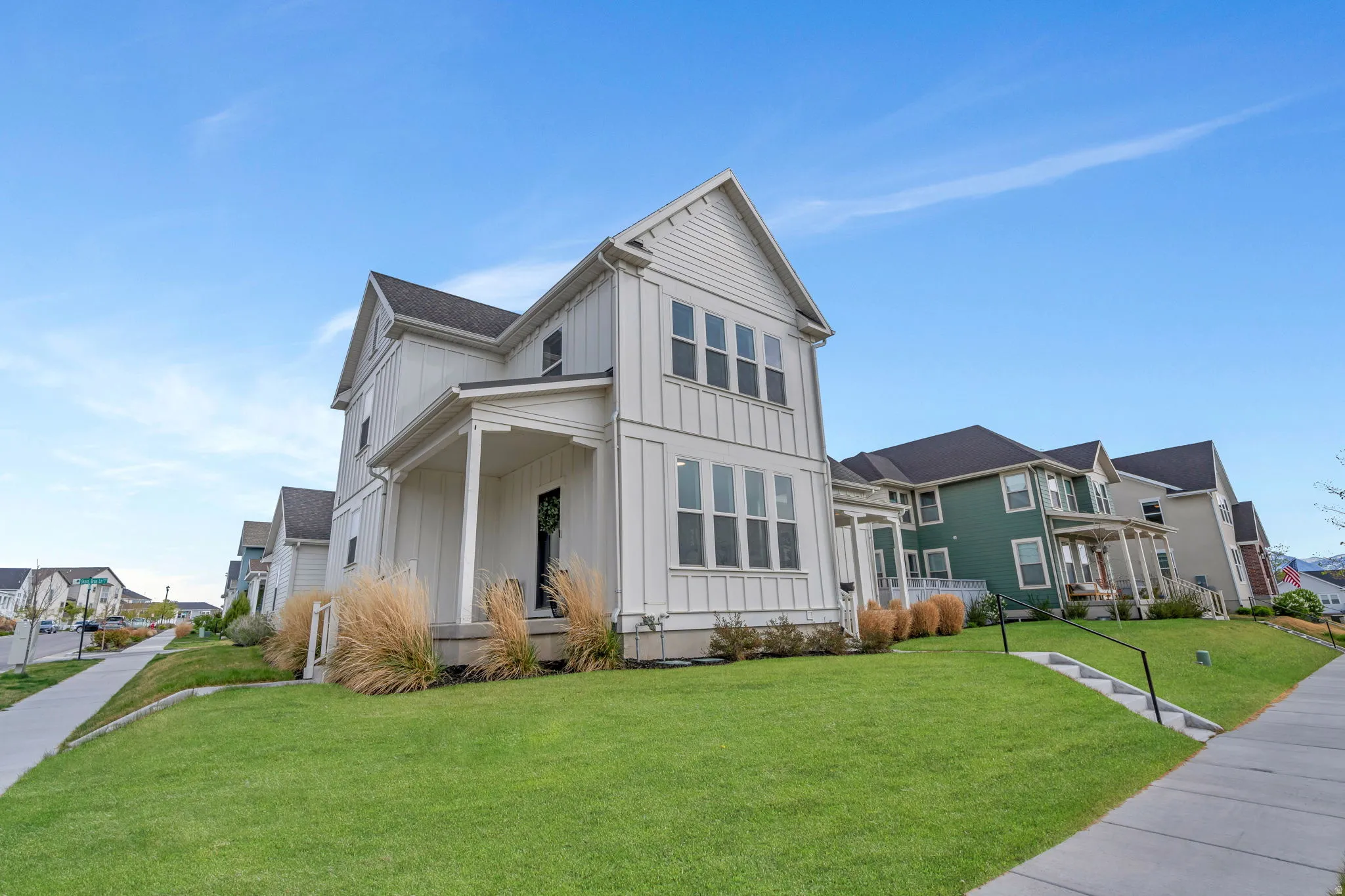 View of front of home with board and batten siding, covered porch, a front yard, and a residential view