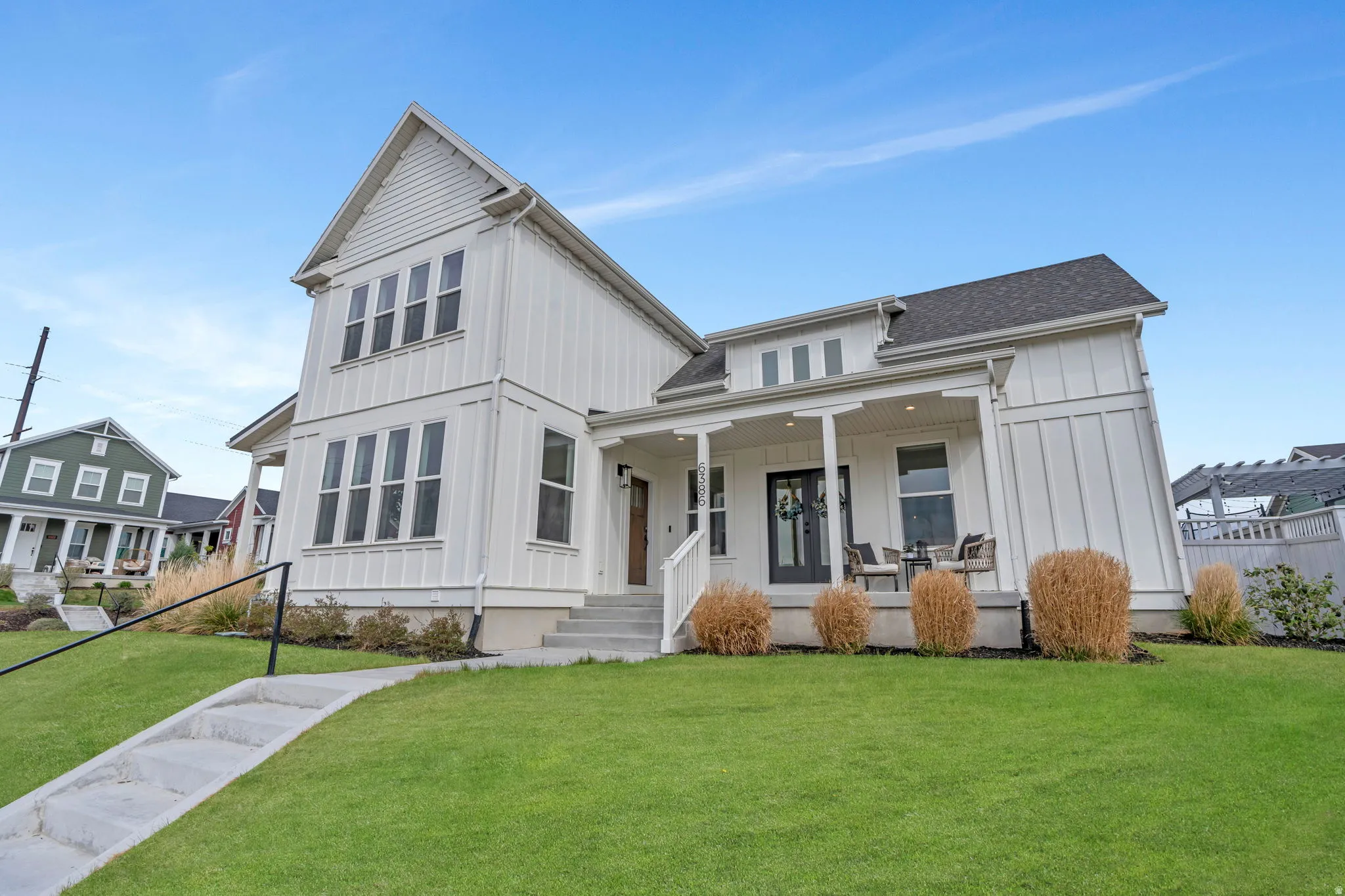 Modern farmhouse with board and batten siding, a porch, and a shingled roof