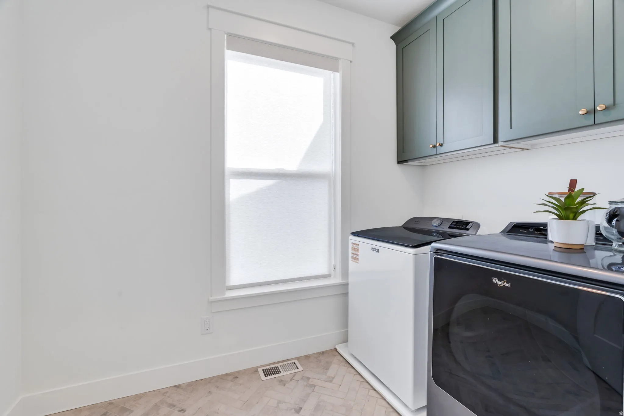 Laundry room featuring washing machine and clothes dryer, parquet floors, and cabinet space