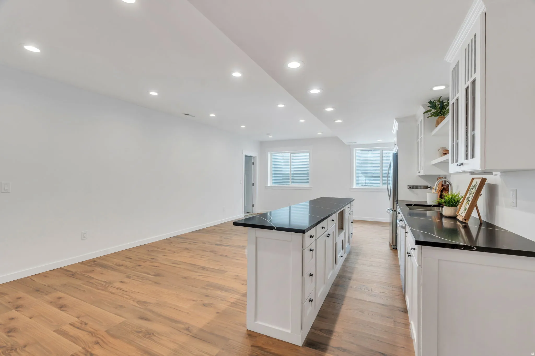 Kitchen featuring dark countertops, open shelves, white cabinets, a center island, and recessed lighting