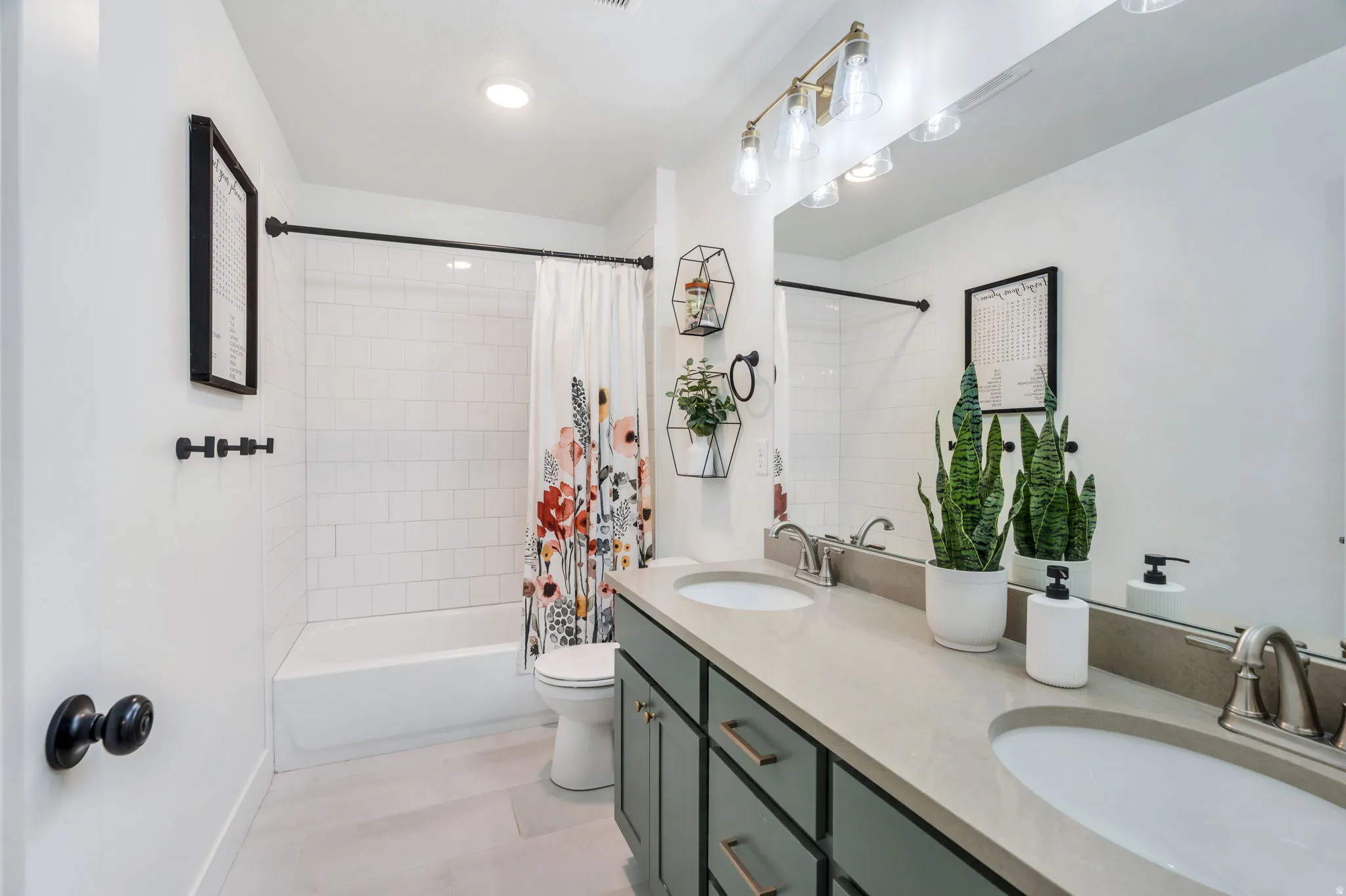 Bathroom featuring double vanity and shower / bathtub combination with curtain