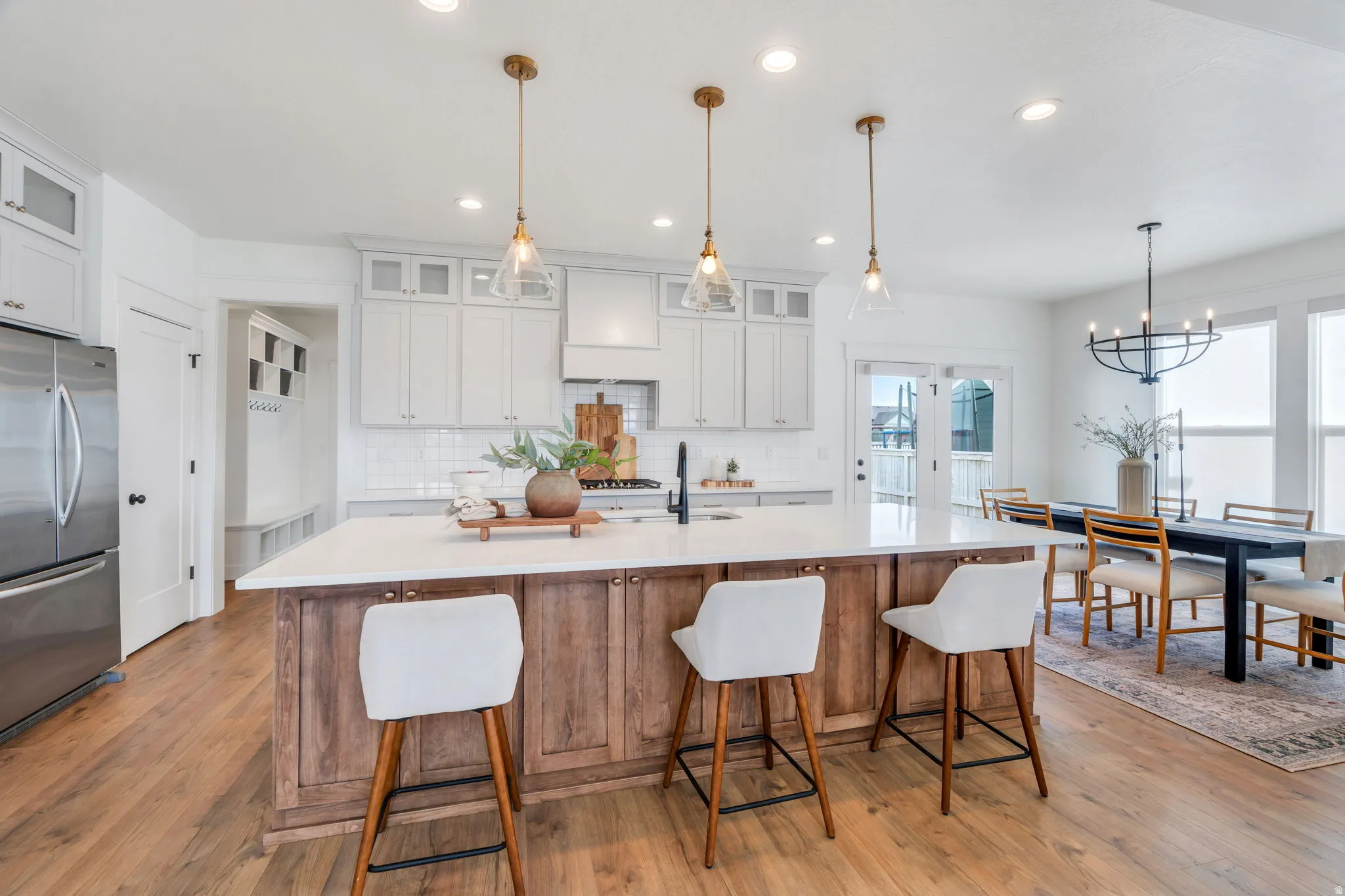 Dual tone kitchen with freestanding refrigerator, glass fronted cabinets, light wood-type flooring, and dual tone cabinetry