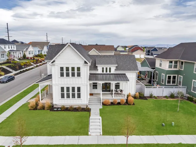 View of front facade with board and batten siding, a residential view, a shingled roof, a front lawn, and a porch
