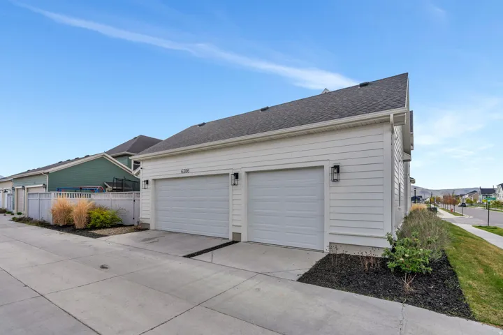View of side of property featuring driveway, roof with shingles, and a garage