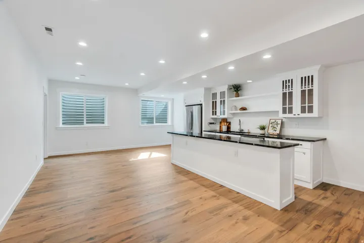Kitchen with open shelves, white cabinets, glass fronted cabinets, light wood-style floors, and recessed lighting