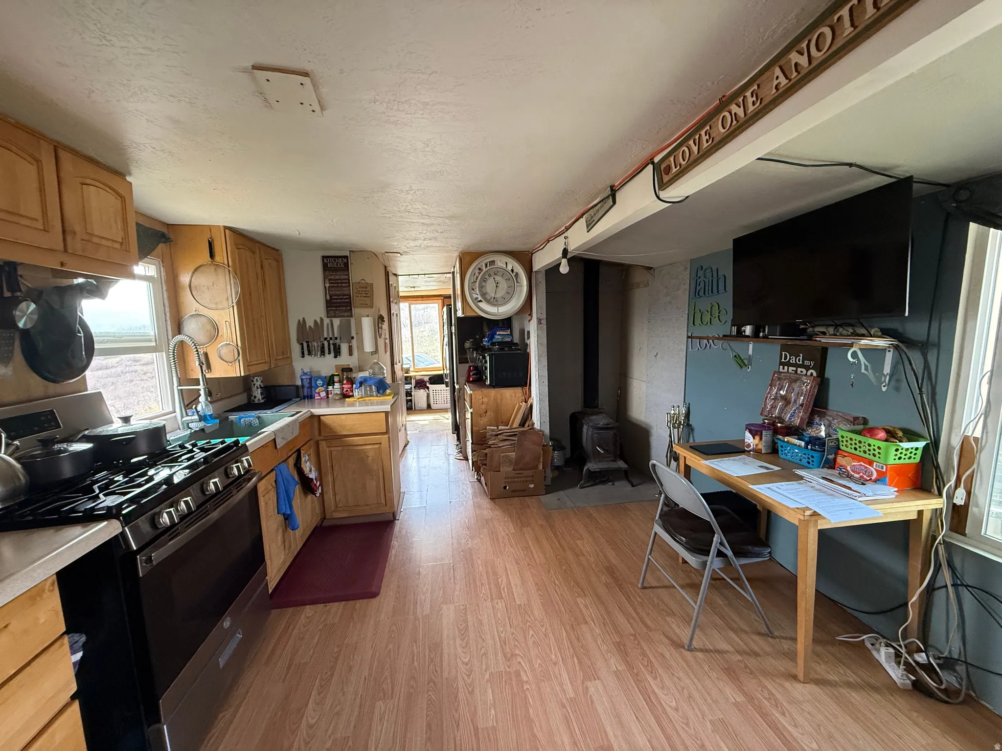 Kitchen featuring stainless steel gas stove, light countertops, a wood stove, light wood-style floors, and a textured ceiling