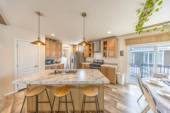 Kitchen featuring a kitchen bar, light countertops, stainless steel appliances, light wood-style flooring, and a center island with sink