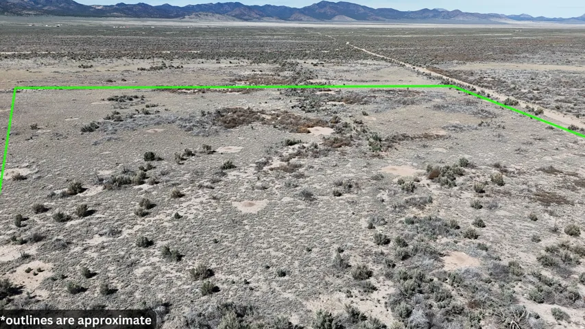 Aerial view of sparsely populated area featuring a mountain backdrop and property parcel outlined