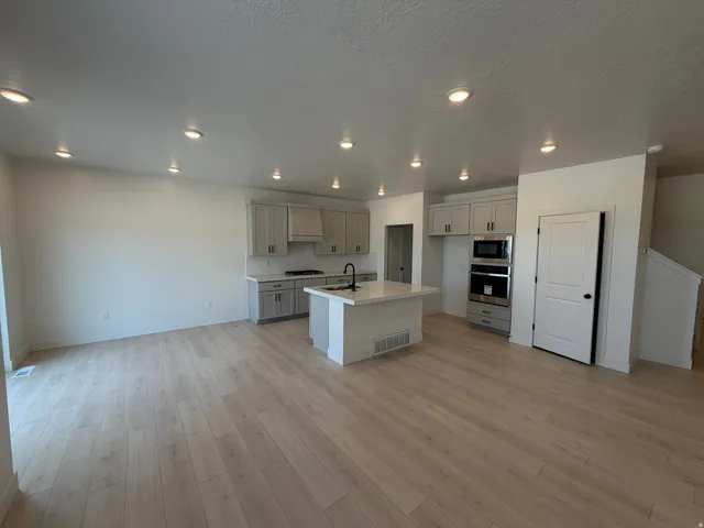 Open-concept main level featuring light wood-finish flooring, recessed lighting, and a modern kitchen