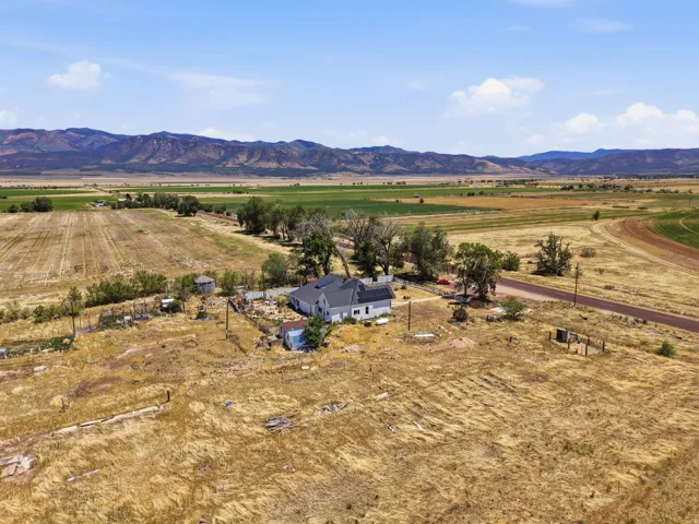 Expansive rural property featuring a white residence with a dark roof