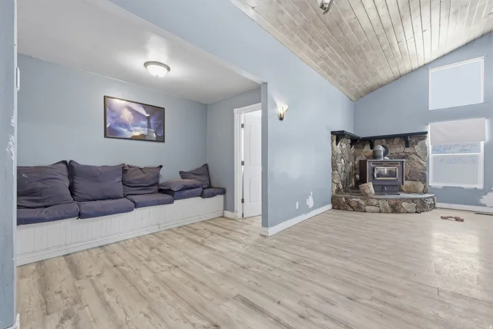 Vaulted wood-finish ceiling above a stone fireplace with a wood-burning insert
