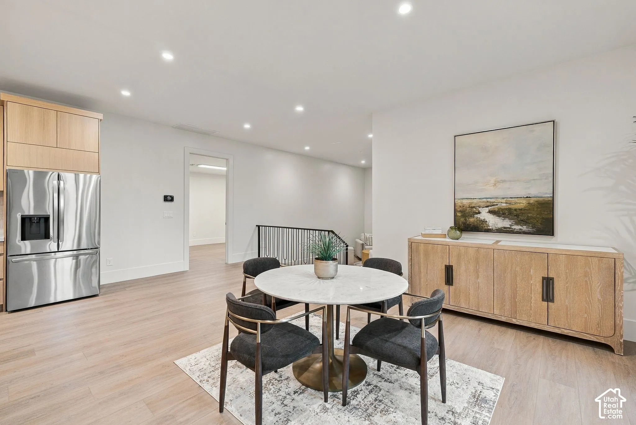 Light wood-finish flooring, recessed lighting, and stainless steel refrigerator